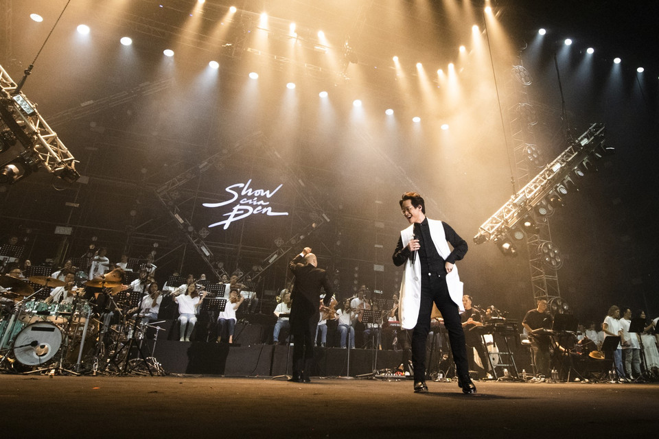 Màn xuất hiện của Hà Anh Tuấn cùng dàn nhạc giao hưởng và dàn hợp xướng lên đến 80 người, chỉ đạo bởi nhạc trưởng Đồng Quang Vinh khiến toàn bộ khán phòng vỡ oà. Mở màn cùng 'Anh đếch cần gì nhiều ngoài em', ngay sau đó, Hà Anh Tuấn dẫn dắt mọi người đến bản mashup: 'Tháng Tư là lời nói dối của em- Trốn tìm-Xuân thì' rồi lại cùng Đen làm mới 'Mang tiền về cho mẹ'. (Ảnh: CTV/Vietnam+)