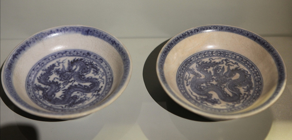  Bộ đĩa gồm 5 chiếc chia làm hai nhóm. Nhóm thứ nhất gồm 4 đĩa lòng sâu có hình dáng tương tự nhau, đều hình cầu, thân uốn cong, miệng loe rộng, men trắng dày phủ kín trong ngoài, mặt ngoài vẽ đôi rồng, lòng đĩa cũng vẽ rồng. (Ảnh: PV/Vietnam+)