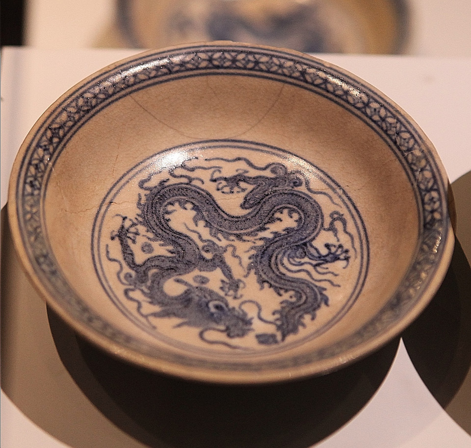  Hình ảnh rồng uy vũ cuộn tròn được vẽ trên đĩa, có 4 chân thể hiện tư thế như đang đạp vào mây với các bắp cơ nổi khối, 5 ngón chân giang rộng với 5 móng sắc nhọn. Đầu rồng ngẩng cao, miệng nhả ngọc, thân uốn thành nhiều khúc. Rồng là sức mạnh thần thánh, là biểu tượng của đế vương. Nó tượng trưng cho vị thế độc tôn của vua chúa và thể hiện quyền lực tối cao của Hoàng đế. (Ảnh: PV/Vietnam+)