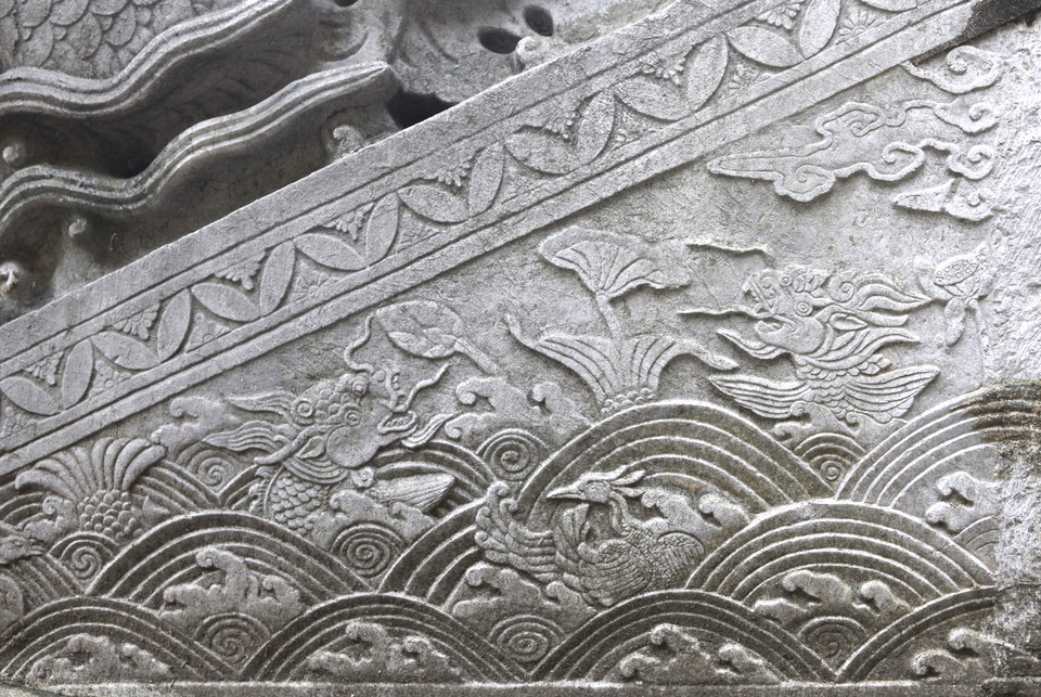 Điểm độc đáo thứ hai ở bậc Điện Kính Thiên thời Lê Trung Hưng chính là đồ án ‘cá hoá rồng’ ở mặt ngoài thành bậc. Đồ án mô tả một hồ sen rộng lớn với nhiều sóng nước xáo động và đùa giỡn trên sóng nước là một đôi uyên ương cùng hai con cá đang hóa rồng. Trong ảnh là cặp cá chép đầu đã thành rồng, đuôi đang còn là đuôi cá, còn thân phần lớn bị chìm khuất dưới nước. (Ảnh: PV/Vietnam+)