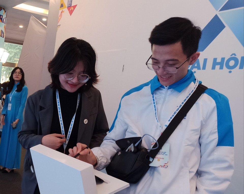 Đại biểu hào hứng viết thông điệp lên màn hình nhỏ và thông điệp cùng hiệu ứng sẽ xuất hiện trên màn hình lớn. (Ảnh: PV/Vietnam+)