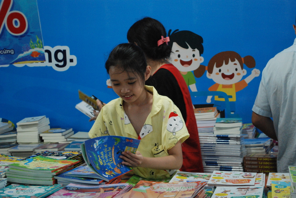 Không ít các bạn nhỏ tranh thủ đọc 'ngấu nghiến' những cuốn sách bày bán tại sự kiện. (Ảnh: PV/Vietnam+)