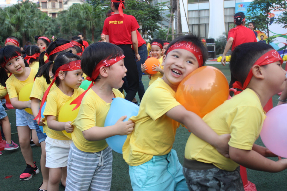 Trò chơi kẹp bóng khiến các bé và cả phụ huynh cười nghiêng ngả. (Ảnh: PV/Vietnam+)