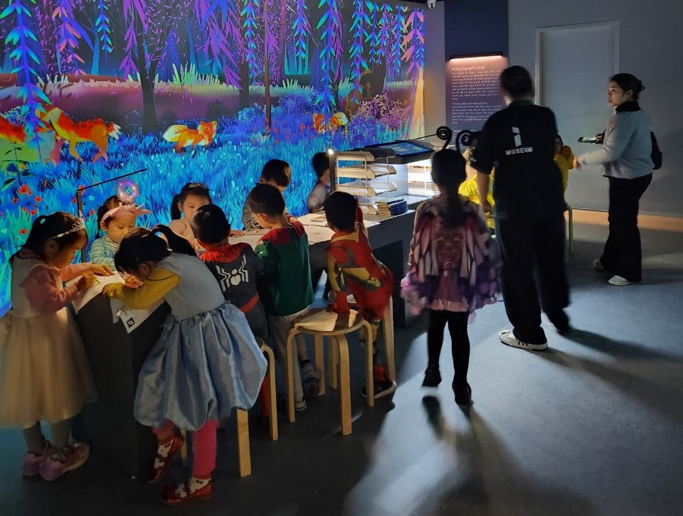 Các em nhỏ trải nghiệm tô màu các loài động vật. Nhờ kết hợp công nghệ 3D Mapping cùng với công cụ trình chiếu, máy quét nhân vật đồ họa, các bức tranh sẽ xuất hiện trên màn hình trên tường, tạo nên một hệ sinh thái độc nhất. (Ảnh: CTV/Vietnam+)