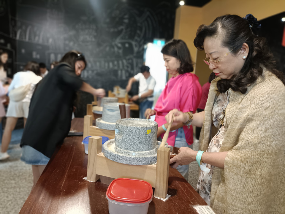 Hoặc tự tay xay ngũ cốc từ cối đá theo cách truyền thống của người dân bản địa. (Ảnh: PV/Vietnam+)