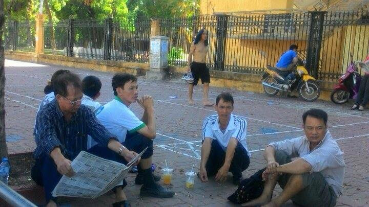 Tại trường Đại học Bách khoa Hà Nội, phụ huynh tránh nắng dưới bóng cây trên vỉa hè, nhưng vẫn không ngăn được cái nóng hầm hập phả từ trên trời xuống, từ dưới mặt đường lên. (Ảnh: Sơn Bách/Vietnam+)