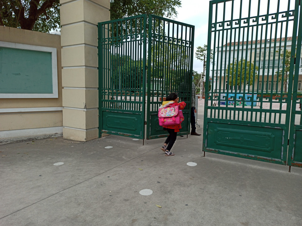 Học sinh chạy vội vào trường khi bác bảo vệ đang từ từ khép cổng phụ. (Ảnh: PM/Vietnam+)