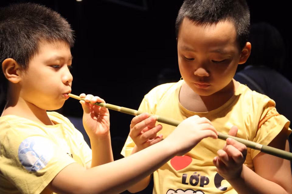 Khán giả nhí tập thổi sáo pi tơm. Nhạc cụ truyền thống của người Khơ Mú gồm nhiều loại, được phân chia theo các bộ như bộ khí (sáo dọc ba lỗ, sáo dọc bốn lỗ, sáo ngang, khèn bè…), bộ gảy (đàn trống, đàn môi…); bộ gõ (ống gõ, cồng chiêng…). (Ảnh: PV/Vietnam+)