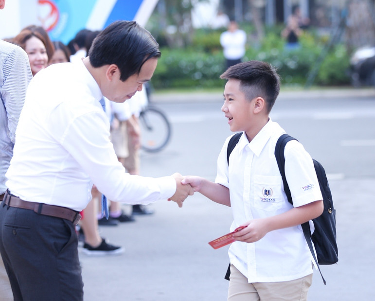 Học sinh được trao những cái bắt tay đầy yêu thương cho một năm học mới. (Ảnh: CTV/Vietnam+)