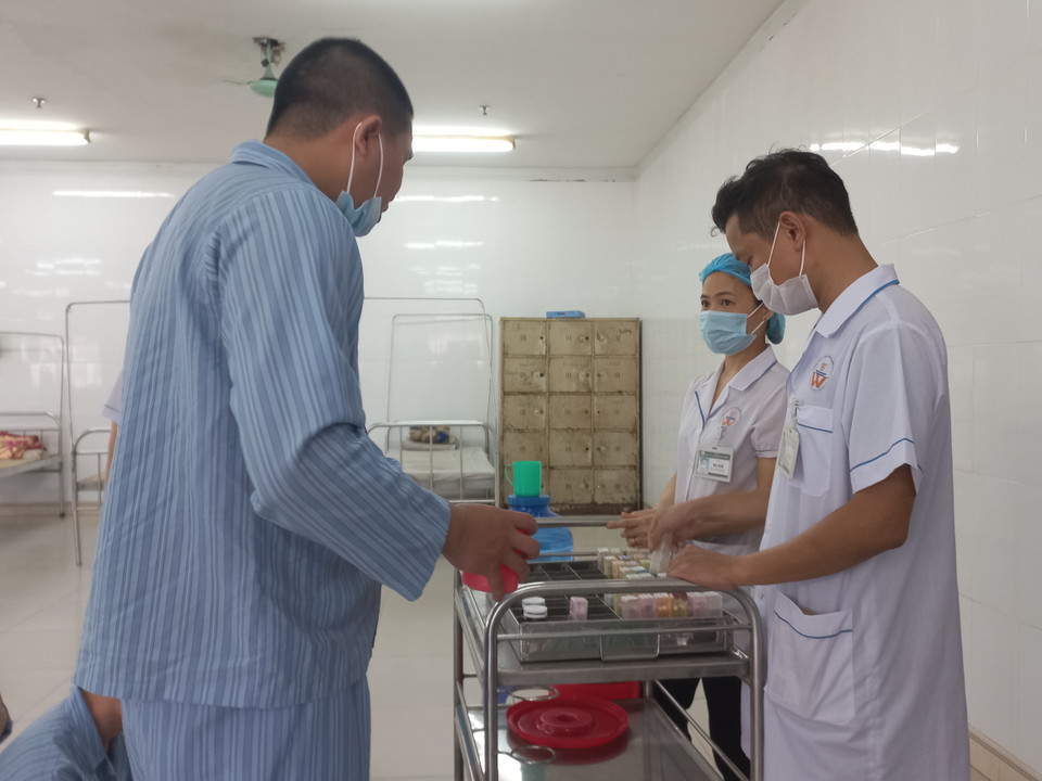 Bệnh nhân được nhân viên y tế kiểm tra bằng cách há miệng sau khi uống thuốc. (Ảnh: PV/Vietnam+)