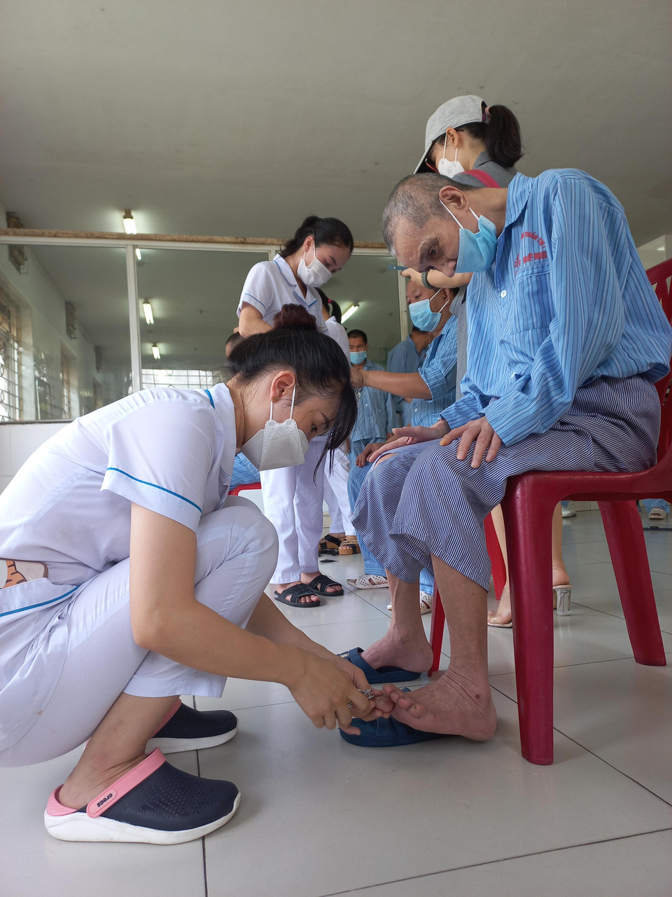 Các bệnh nhân được nhân viên y tế cắt móng chân. (Ảnh: PV/Vietnam+)