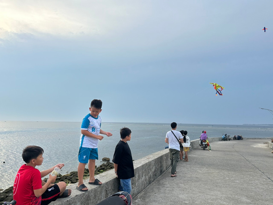 Khung cảnh thơ mộng nơi những em bé thả diều giữa biển khơi: Một bên là biển rộng, một bên là cảng neo đậu tàu thuyền đa sắc màu. (Ảnh: PV/Vietnam+)