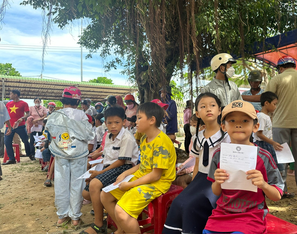 Các em nhỏ ngồi xếp hàng chờ đợi khám chữa bệnh và lấy thuốc cũng như các phần quà. (Ảnh: PV/Vietnam+)