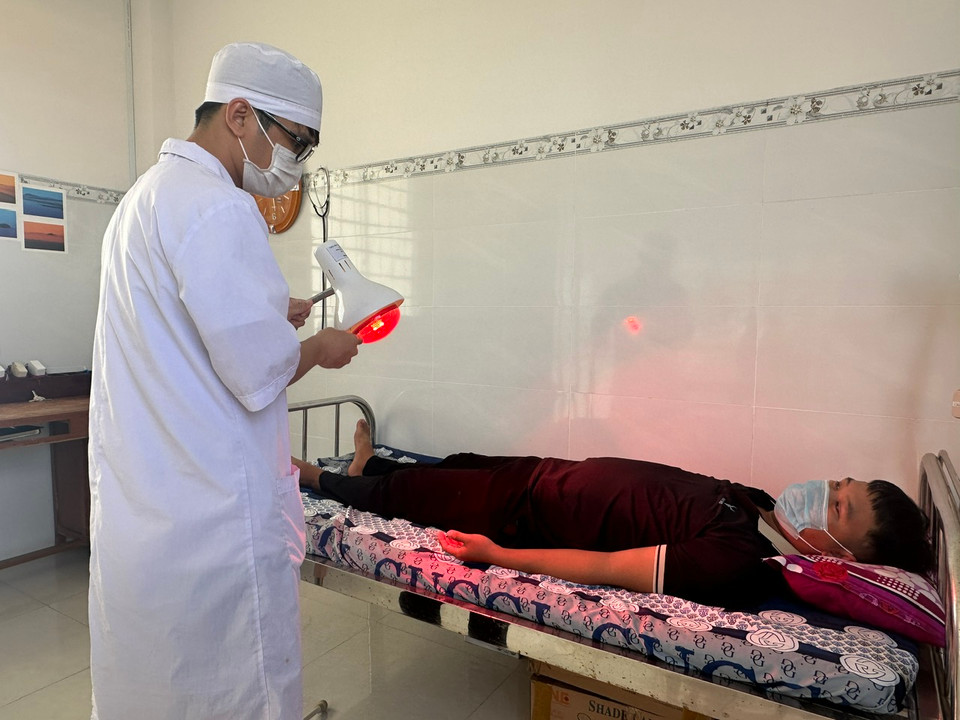 Nhân viên y tế chuyên ngành y học cổ truyền tại Trạm Y tế chiếu đèn điều trị cho người bệnh. (Ảnh: T.G/Vietnam+)