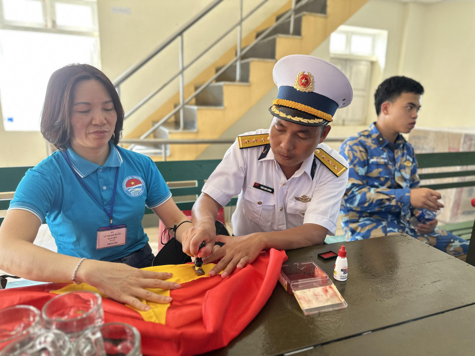 Một Kiều bào tại Ba Lan trân trọng đóng con dấu của đảo Đá Tây B lên lá cờ Tổ quốc để làm kỷ niệm. (Ảnh: Thùy Giang/Vietnam+)