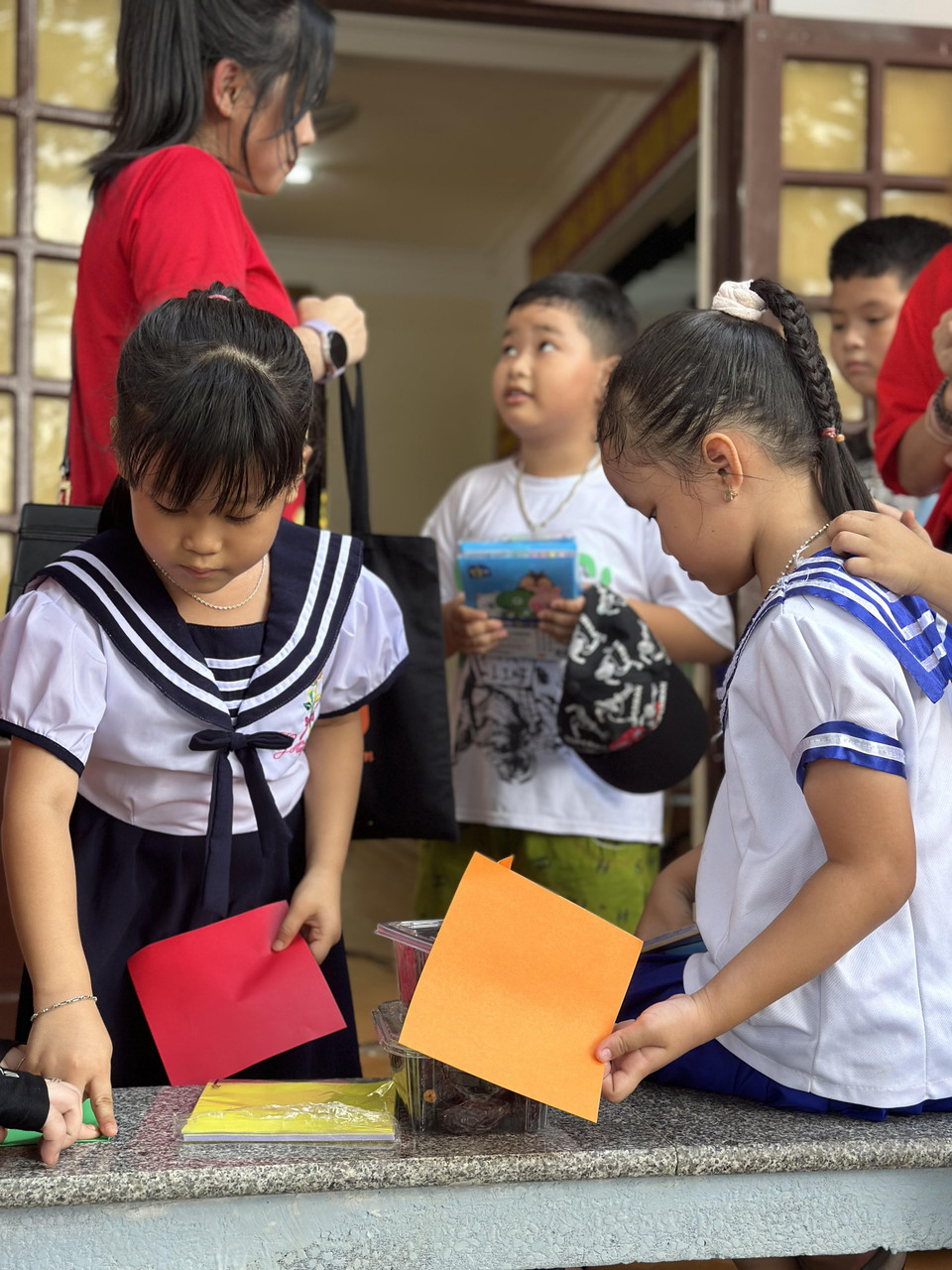 Những đứa trẻ thích thú với các tờ giấy màu để gấp đồ chơi. (Ảnh: Thùy Giang/Vietnam+)