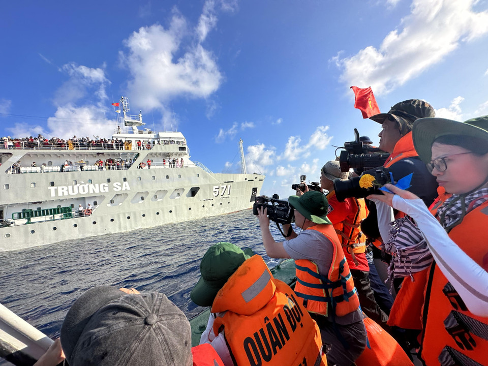 Các nhà báo xuống xuồng chụp ảnh, ghi hình Đoàn công tác số 4 làm lễ tưởng niệm các chiến sỹ đã hy sinh trên vùng biển Gạc Ma, Cô Lin. (Ảnh: Thùy Giang/vietnam+)