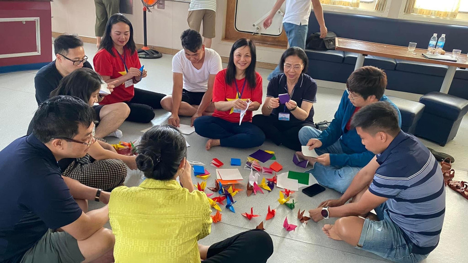 Kiều bào và các thành viên của đoàn công tác số 4/2023 gấp hạc giấy trên Tàu 571 cho buổi Lễ tưởng niệm các chiến sỹ hy sinh trên khu vực biển Gạc Ma-Cô Lin. (Ảnh: PV/Vietnam+)