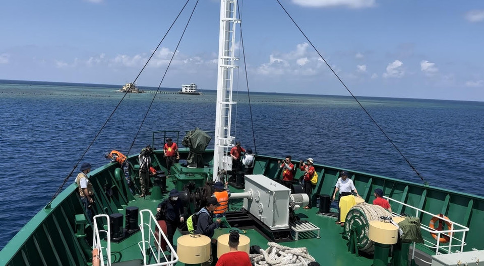 Các nhà báo chụp ảnh, quay phim khi Tàu 571 thả neo để chuẩn bị đưa các đoàn đại biểu vào đảo. (Ảnh: PV/Vietnam+)