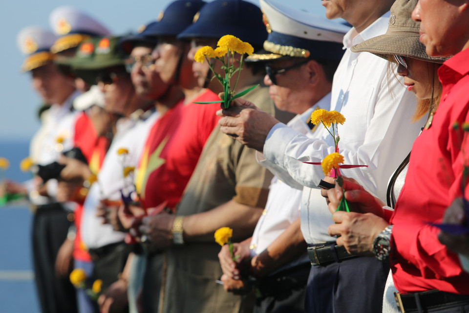 Những bông hoa cúc vàng được mọi người nâng niu để thả xuống biển tưởng nhớ đến các liệt sĩ đã vì Tổ quốc mà hy sinh, nằm lại nơi biển cả xa xôi. (Ảnh: Hồng Sơn/Vietnam+)