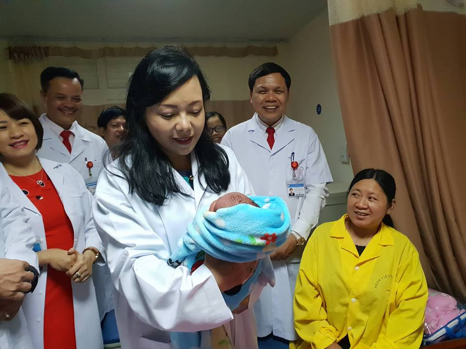 Người đứng đầu ngành y tế bế và tặng quà cho trẻ sơ sinh trong đêm 30 Tết. (Ảnh: T.G/Vietnam+)