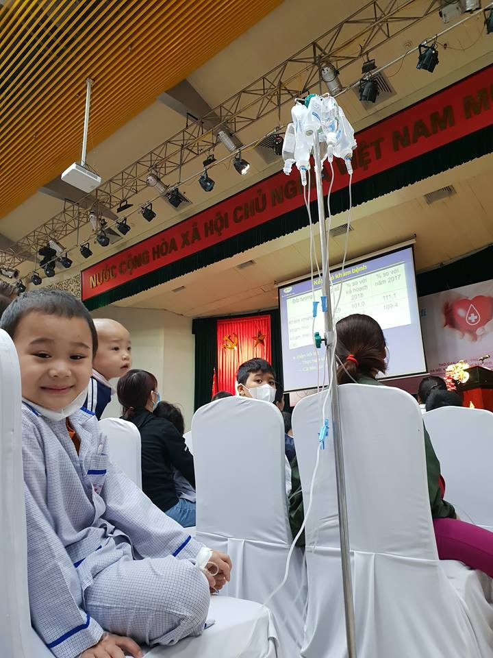 Các em nhỏ mang theo cả chai truyền. (Ảnh: PV/Vietnam+) 