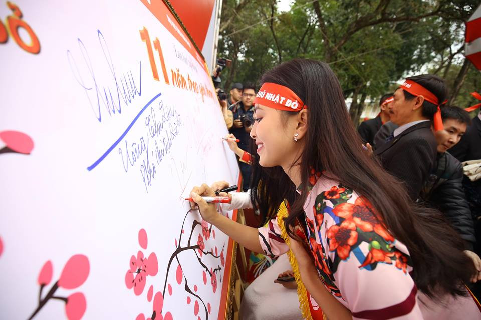 Hoa hậu Tiểu Vy ký tên lưu niệm trên bức trướng Trái tim yêu thương. (Ảnh: PV/Vietnam+)