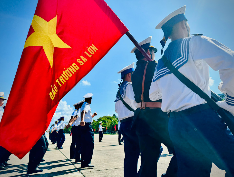 Trước cột mốc chủ quyền, dưới lá cờ đỏ thắm trên đảo Trường Sa, lời Quốc ca vang lên hùng tráng, thiêng liêng đầy kiêu hãnh và tự hào giữa bốn bề sóng vỗ. (Ảnh: Nguyễn Trần Tùng/Vietnam+)