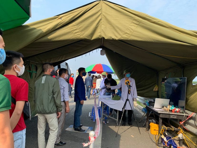 Đo thân nhiệt cho mọi người dân khi qua trạm kiểm soát. (Ảnh: Thuỳ Giang/Vietnam+)