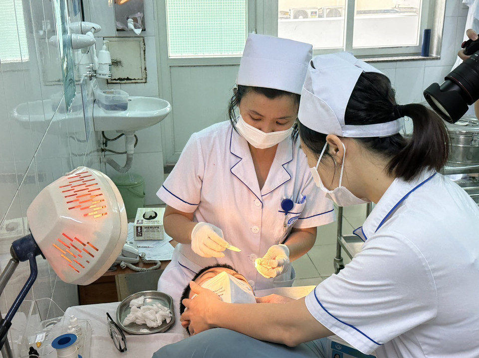 Các y bác sỹ thực hiện thủ thuật bóc giả mạc cho bệnh nhi. (Ảnh: T.G/Vietnam+)