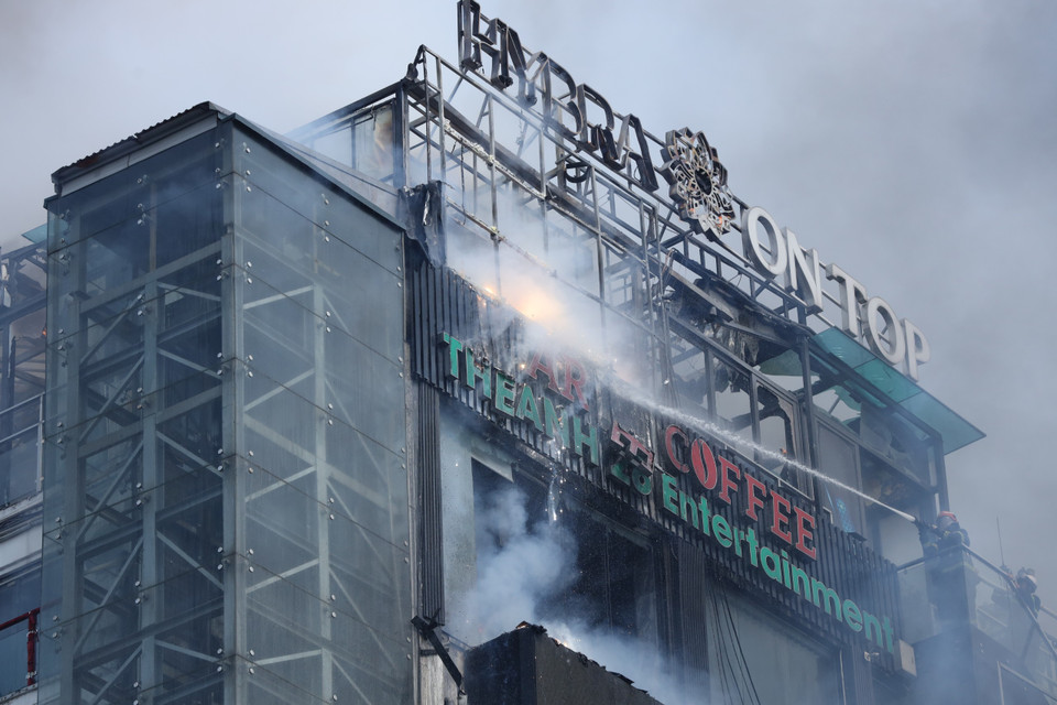 Ngọn lửa vẫn đang cháy từ phía trên nóc của tòa nhà. (Ảnh: Hoài Nam/Vietnam+)