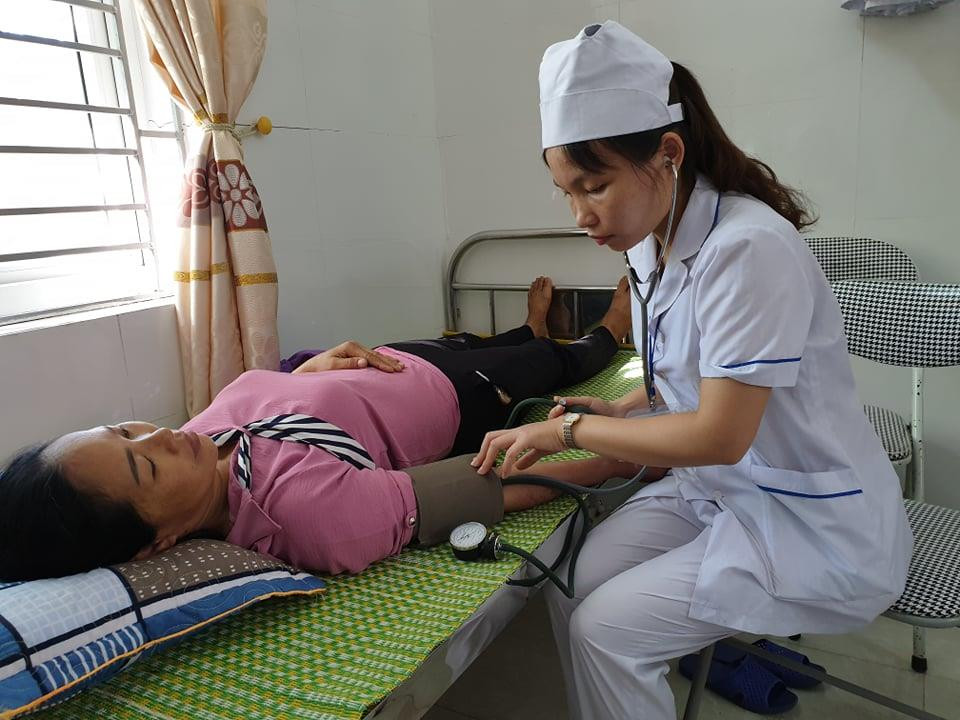 Nhân viên trạm y tế đo huyết áp cho người dân tới khám. (Ảnh: PV/Vietnam+)