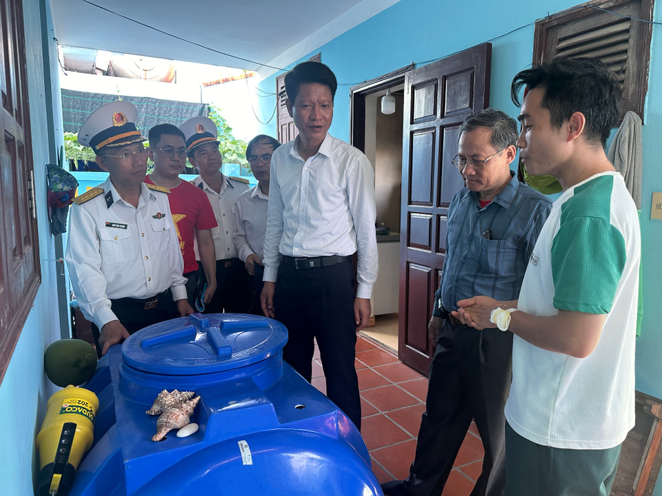 Một người dân sống trên đảo giới thiệu với Lãnh đạo Đoàn Công tác số 21 về cách lưu giữ nước ngọt từ nguồn nước mưa để sử dụng. (Ảnh: Thùy Giang/Vietnam+)