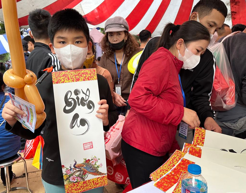 Một em nhỏ hân hoan với tấm thư pháp được tặng. (Ảnh: T.G/Vietnam+)