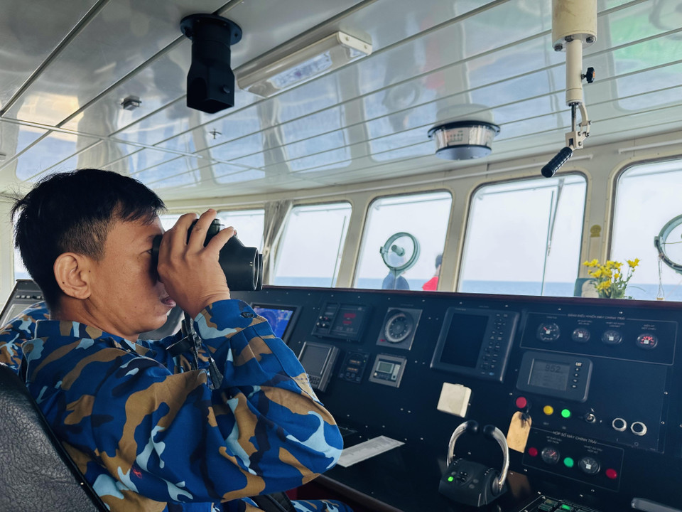 Thuỷ thủ trưởng Tàu 571 Nguyễn Sỹ Hà quan sát bằng ống nhòm khi có một tàu phía trước sắp đi ngang qua. (Ảnh: Thùy Giang/Vietnam+)