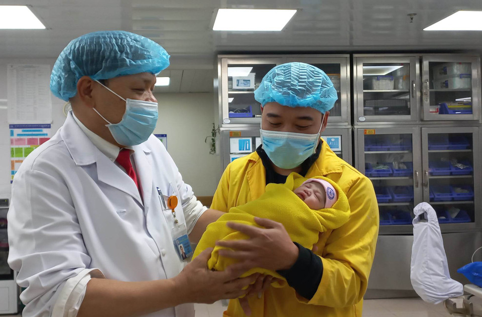 Phó giáo sư Trần Danh Cường - Giám đốc Bệnh viện Phụ sản Trung ương trao bé gái cho người bố. (Ảnh: T.G/Vietnam+)