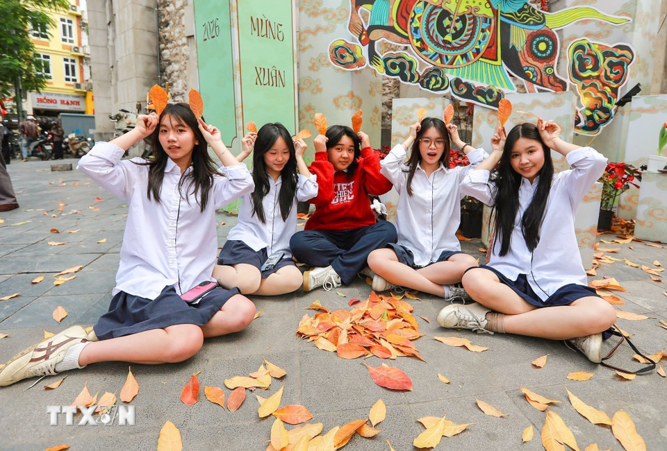 Các bạn trẻ lưu lại khoảnh khắc nên thơ trong sắc lá vàng của mùa cây thay lá. (Ảnh: Khánh Hòa/TTXVN)
