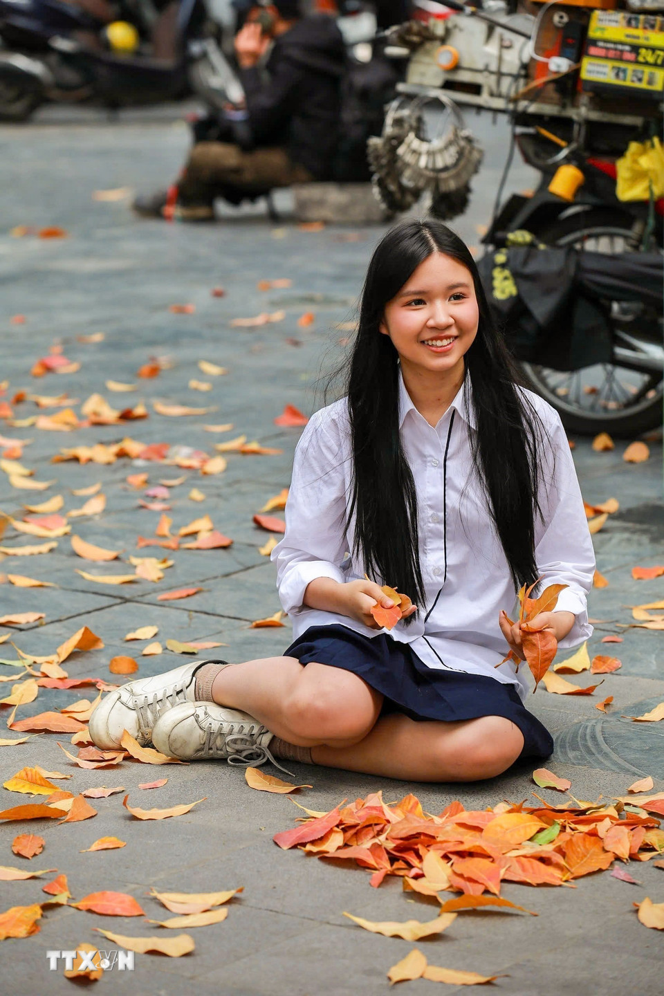 Các bạn trẻ lưu lại khoảnh khắc nên thơ trong sắc lá vàng của mùa cây thay lá. (Ảnh: Khánh Hòa/TTXVN)