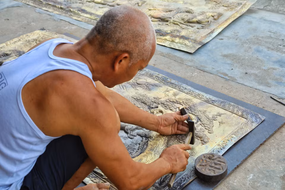 Người thợ tỉ mẩn chạm khắc, tạo hình họa tiết tinh xảo trên một bức tranh đồng lớn. Công việc đòi hỏi sự kiên nhẫn và đôi tay lành nghề. (Ảnh: Phương Anh/TTXVN phát)