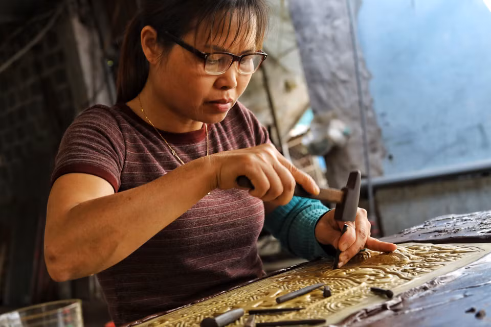 Người thợ tỉ mỉ chạm khắc từng đường nét trên tấm bạc, giữ gìn kỹ thuật thủ công truyền thống đã tồn tại hàng trăm năm. (Ảnh: Phương Anh/TTXVN phát)