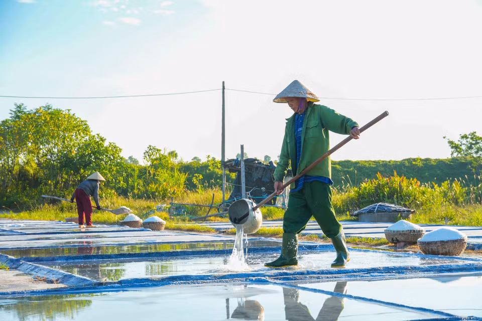 Diêm dân đổ nước lên các ô nại để chuẩn bị cho việc thu hoạch muối vào ngày tiếp theo. (Ảnh: Hữu Quyết/TTXVN)