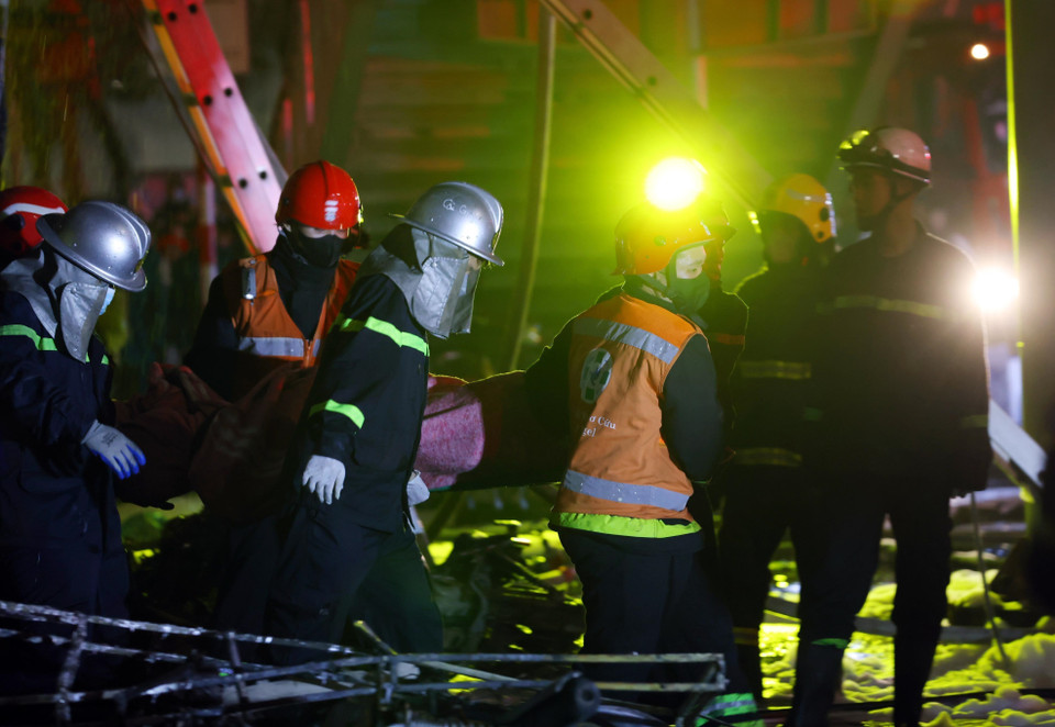 Lực lượng chức năng đưa thi thể nạn nhân thiệt mạng ra khỏi hiện trường vụ cháy. (Ảnh: Phạm Kiên/TTXVN)