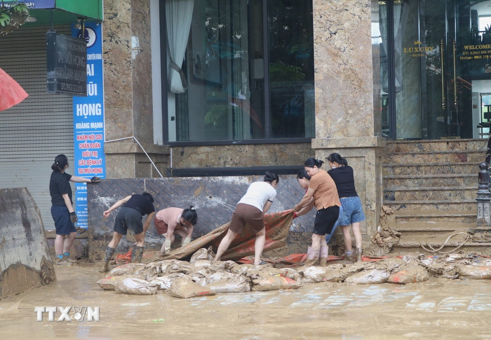 Người dân vùng ngập lụt tranh thủ dọn dẹp khi nước đã rút. (Ảnh: Chu Hiệu/TTXVN)