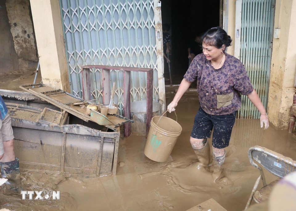 Người dân vùng ngập lụt tranh thủ dọn dẹp khi nước đã rút. (Ảnh: Chu Hiệu/TTXVN)