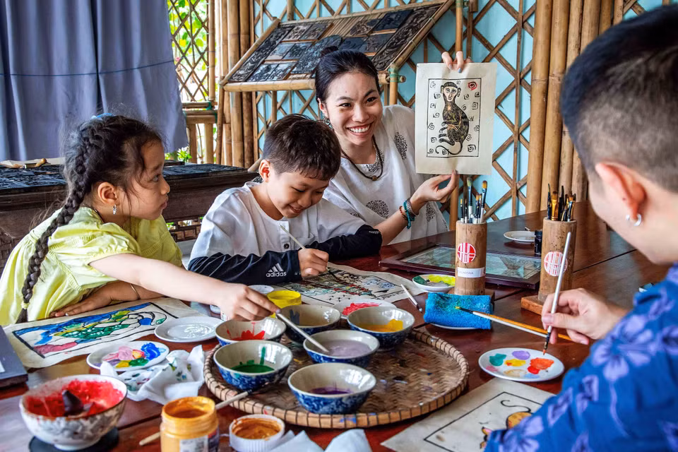 Du khách thích thú khi tự tay hoàn thiện một bức tranh làng Sình. (Ảnh: Vân Chi/TTXVN phát) ​