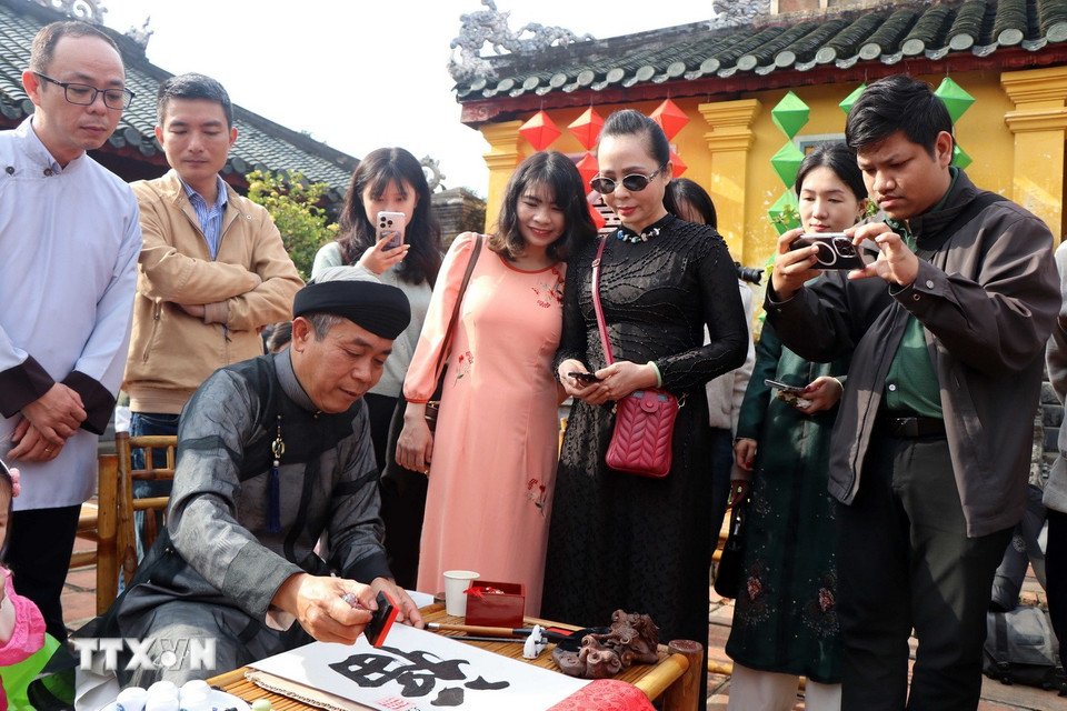 Du khách xin chữ thư pháp, mong cầu một năm mới mạnh khỏe, bình an. (Ảnh: Đỗ Trưởng/TTXVN)