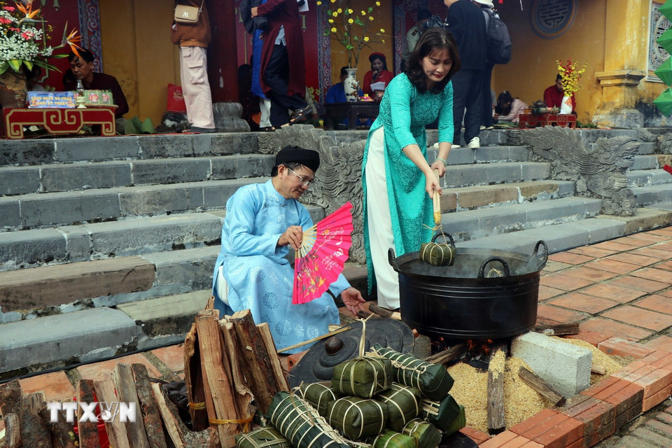 Du khách thích thú trải nghiệm luộc bánh chưng ngày Tết ở Cung Trường Sanh trong Đại Nội Huế. (Ảnh: Đỗ Trưởng/TTXVN)