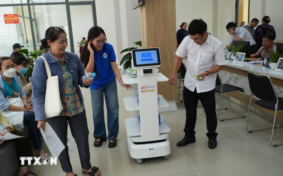 Người dân vui vẻ với những câu nói ngộ nghĩnh, hài hước của robot lễ tân tại phường Thủ Đức. (Ảnh: Hữu Duyên/TTXVN)