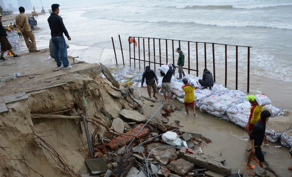 Hơn 200 nhân lực khẩn trương làm kè tạm bằng bao cát, ngăn không cho sóng tiếp tục đánh vào bờ. (Ảnh: Văn Dũng/TTXVN)