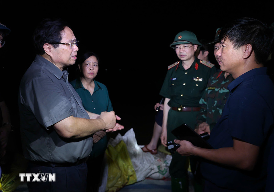 Thủ tướng Phạm Minh Chính động viên lực lượng đang đắp chống tràn, bảo đảm an toàn tuyến đê hữu Cầu. (Ảnh: Dương Giang/TTXVN)